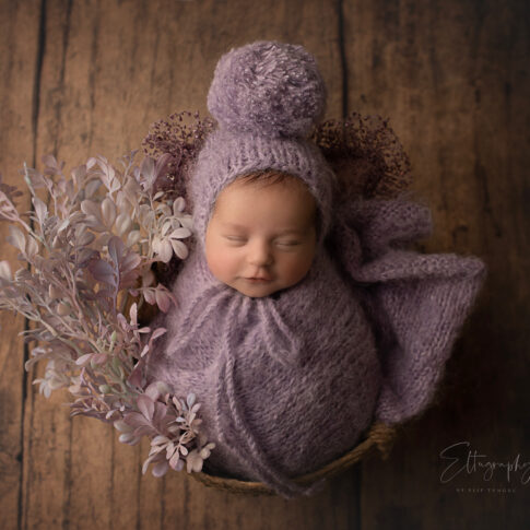 newborn baby shooting photo with purple baby dress concept in basket