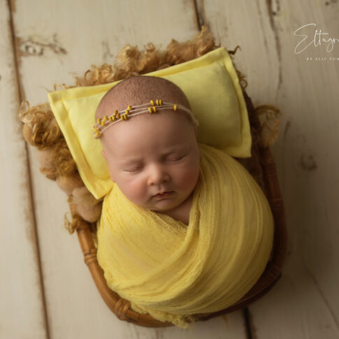 neugeborenes babyfoto mit gelbem babykleid