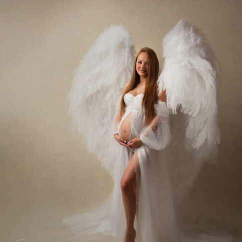 Maternity photo on cream background with gorgeous angel maternity dress